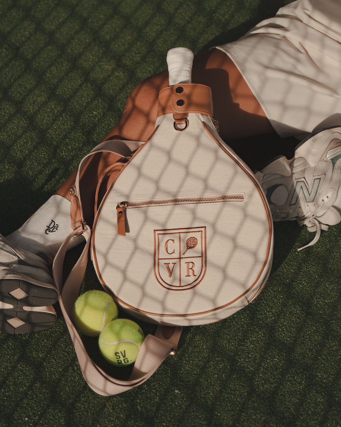 Ginger COVR padel racket cover lying on a padel court with two balls