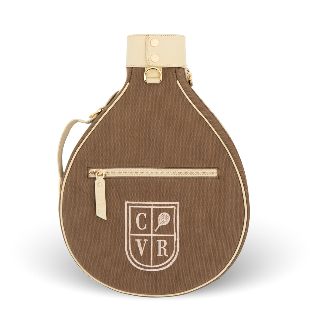 A brown teardrop-shaped tennis bag with cream-colored trim, a top handle, and a front zippered pocket. The front features an embroidered shield crest with the letters 'CVR' and a tennis racket icon.