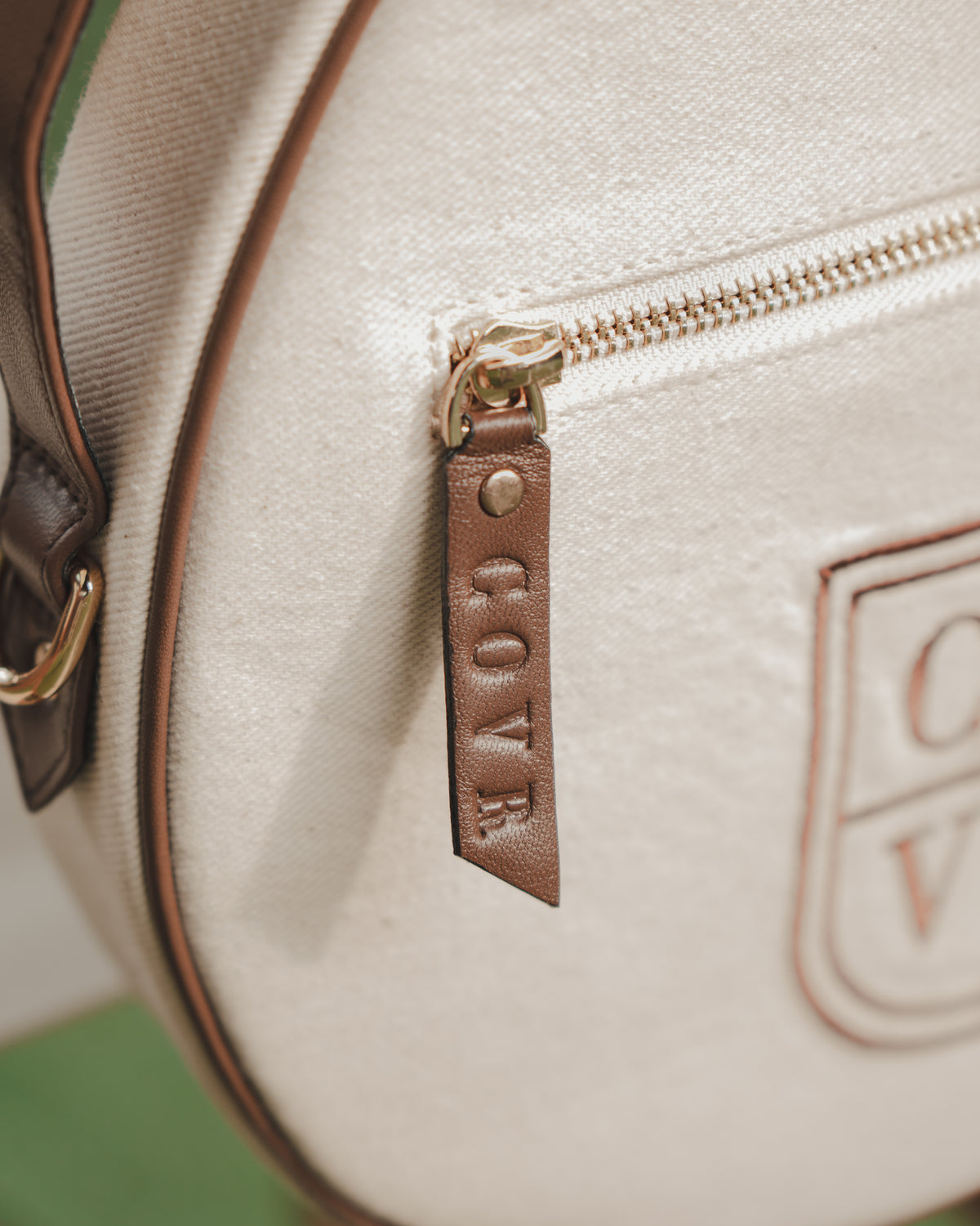 Close-up of the leather zip pull embossed COVR on a cream cover