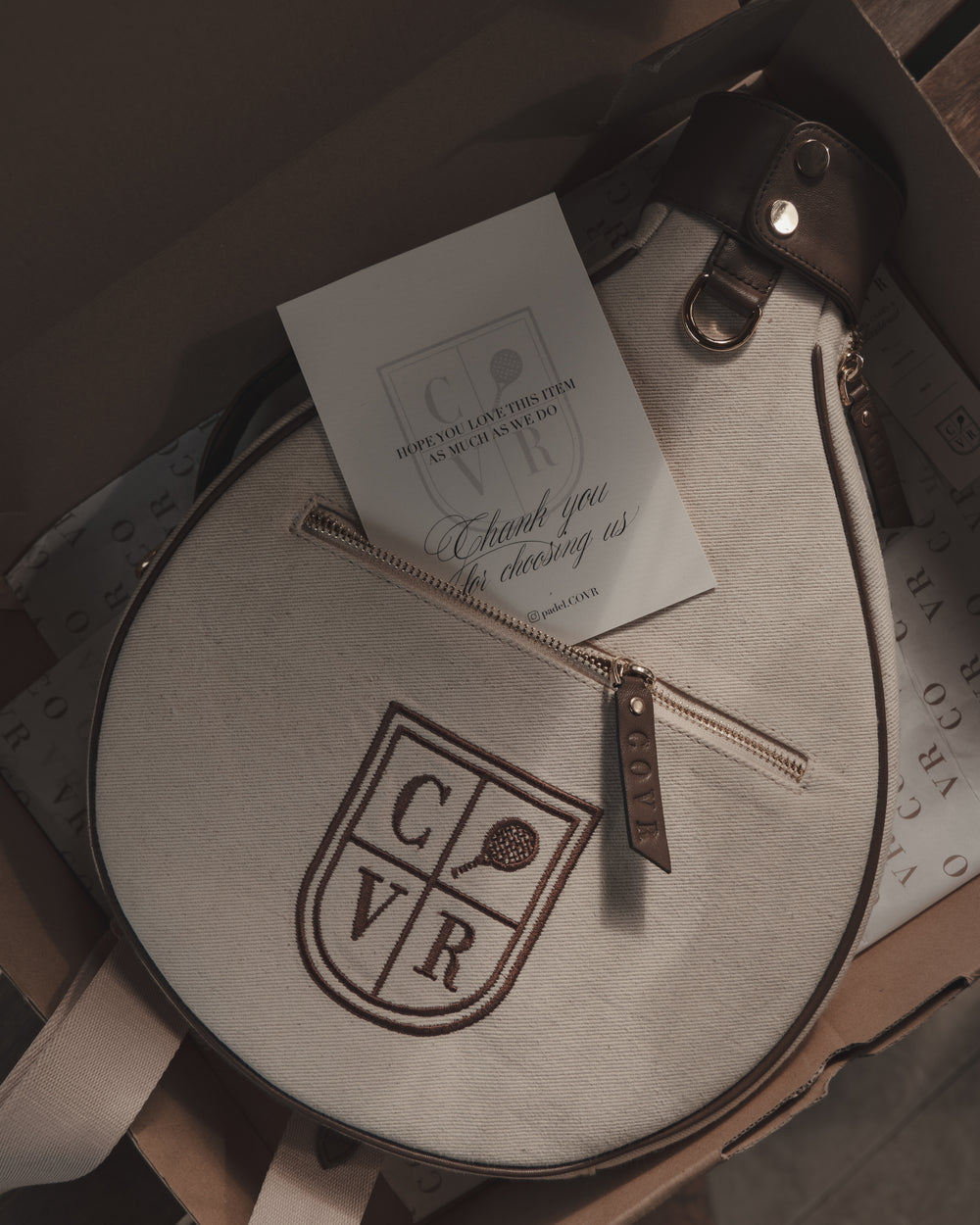 A COVR cover in its box with a thank-you card tucked into the zip pocket