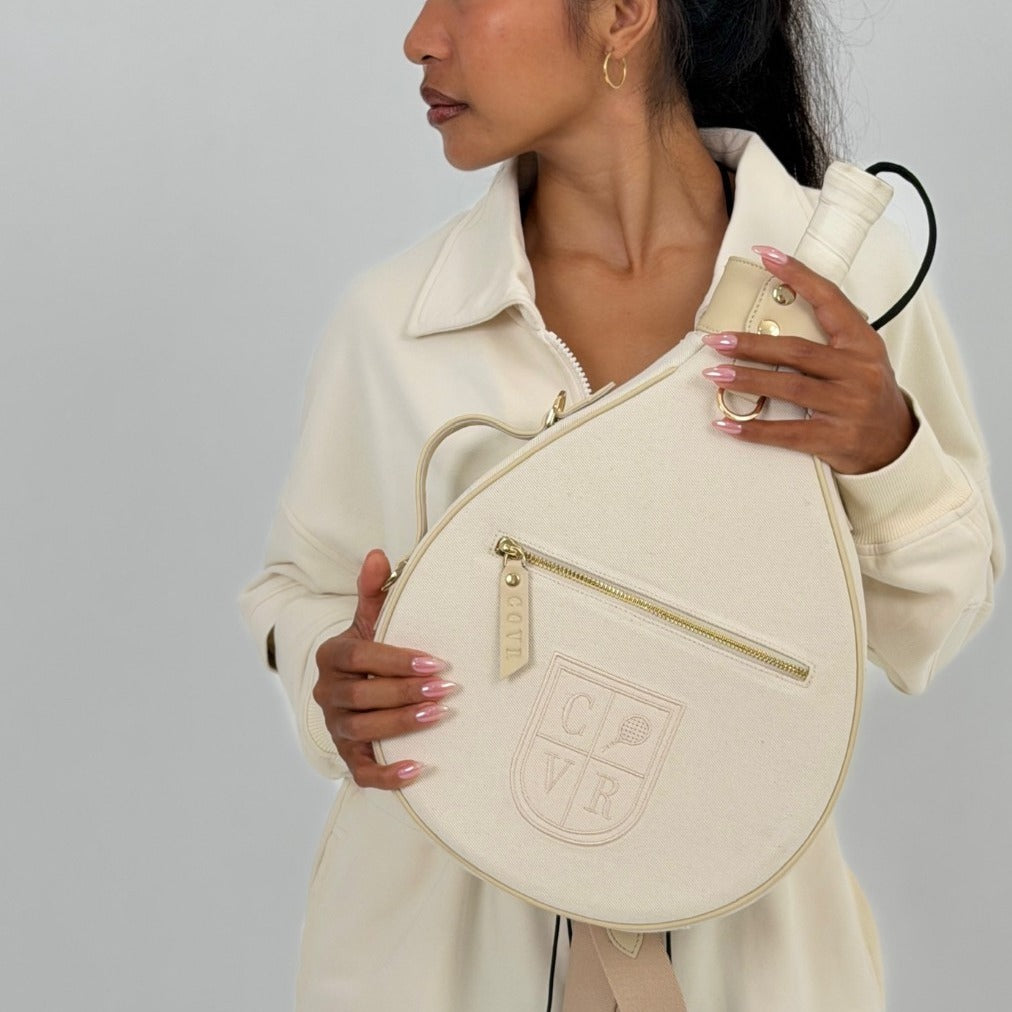 Player in a cream set holding a Vanilla Cream COVR padel racket cover