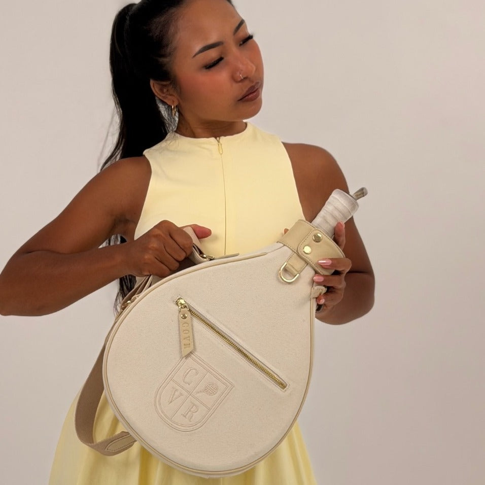 Player in a yellow tennis dress holding a Vanilla Cream COVR padel racket cover