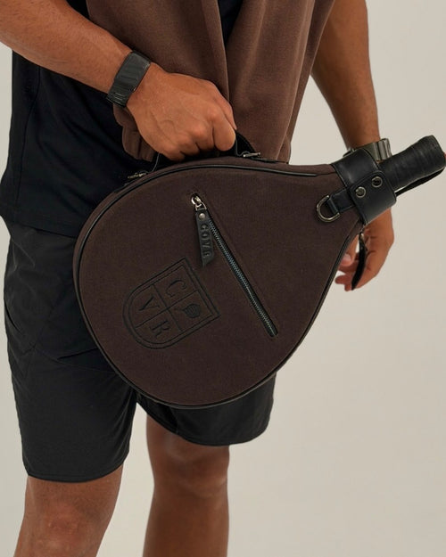 Man carrying a Coffee COVR padel racket cover by its handle